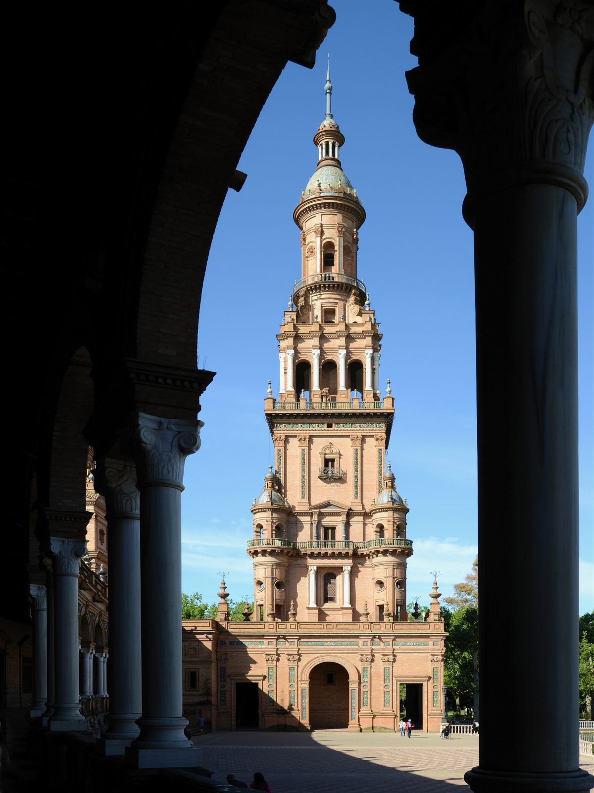 The tower of the Plaza de Espana in Seville seen through its colonnade